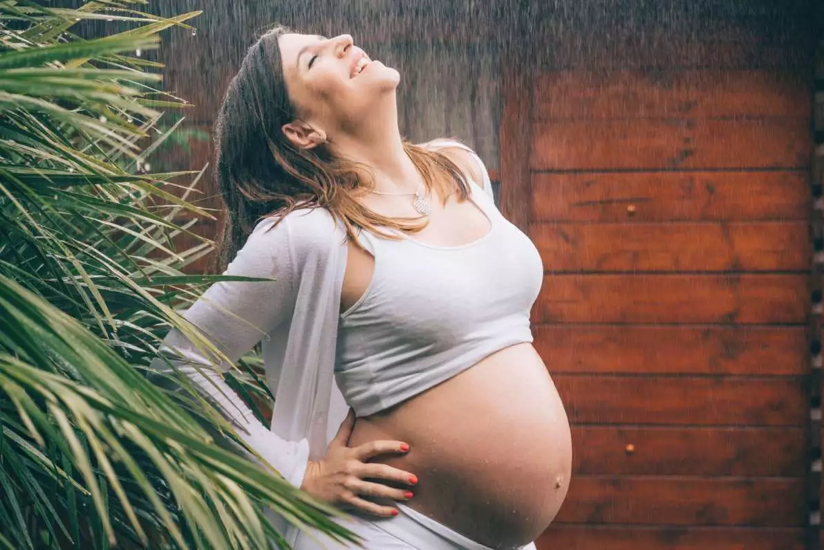 Une femme enceinte heureuse sous la pluie, pleine de vitalité.