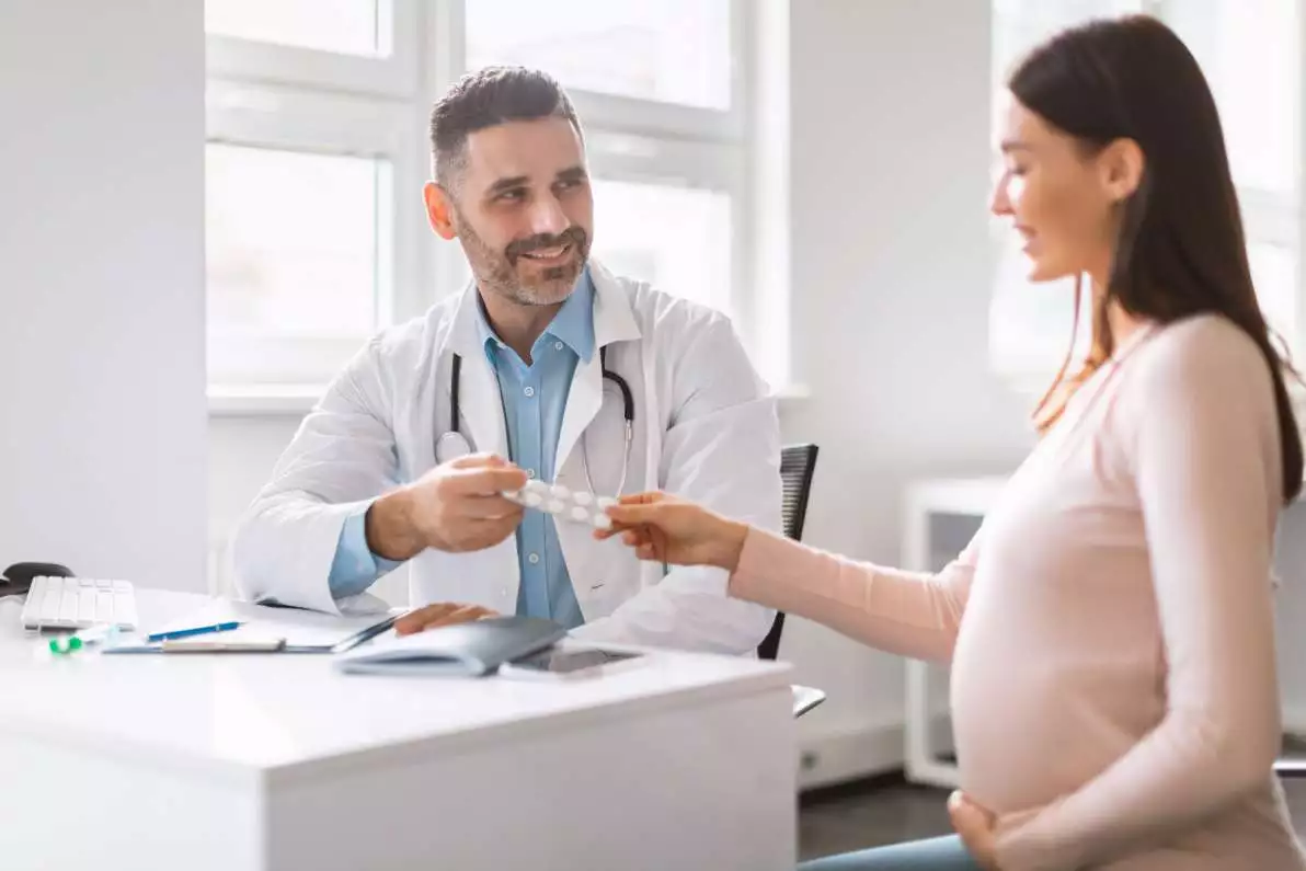 Un professionnel de santé donne des gélules de suppléments à une femme enceinte.