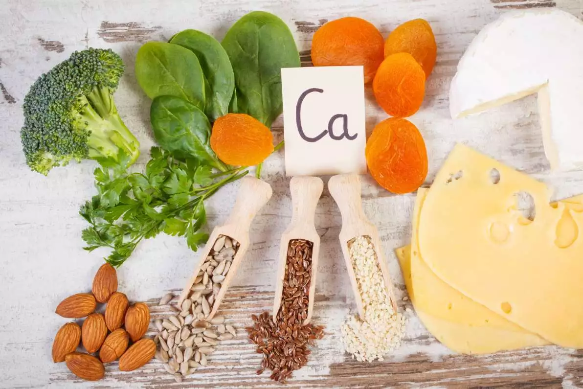 Les aliments source de calcium, comprenant des produits laitiers, des oléagineux et des légumes, sont posés sur une table.