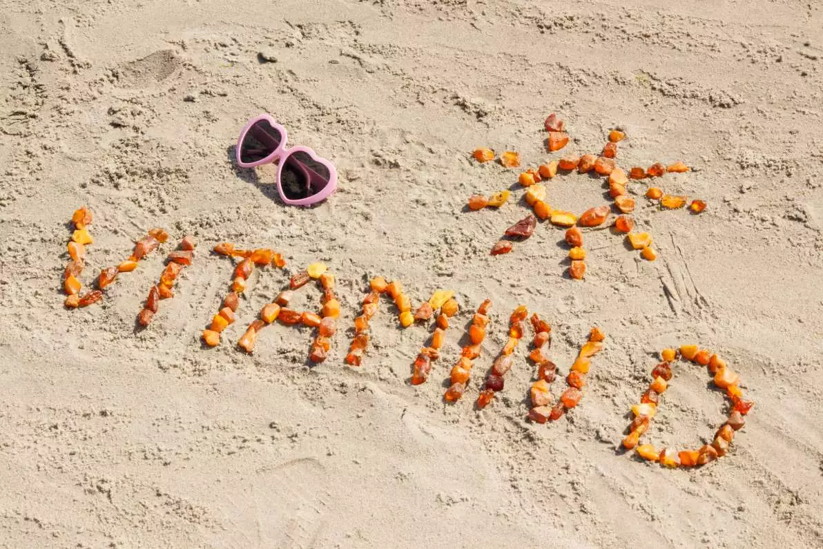 Inscription Vitamine D avec un dessin de soleil sur du sable.