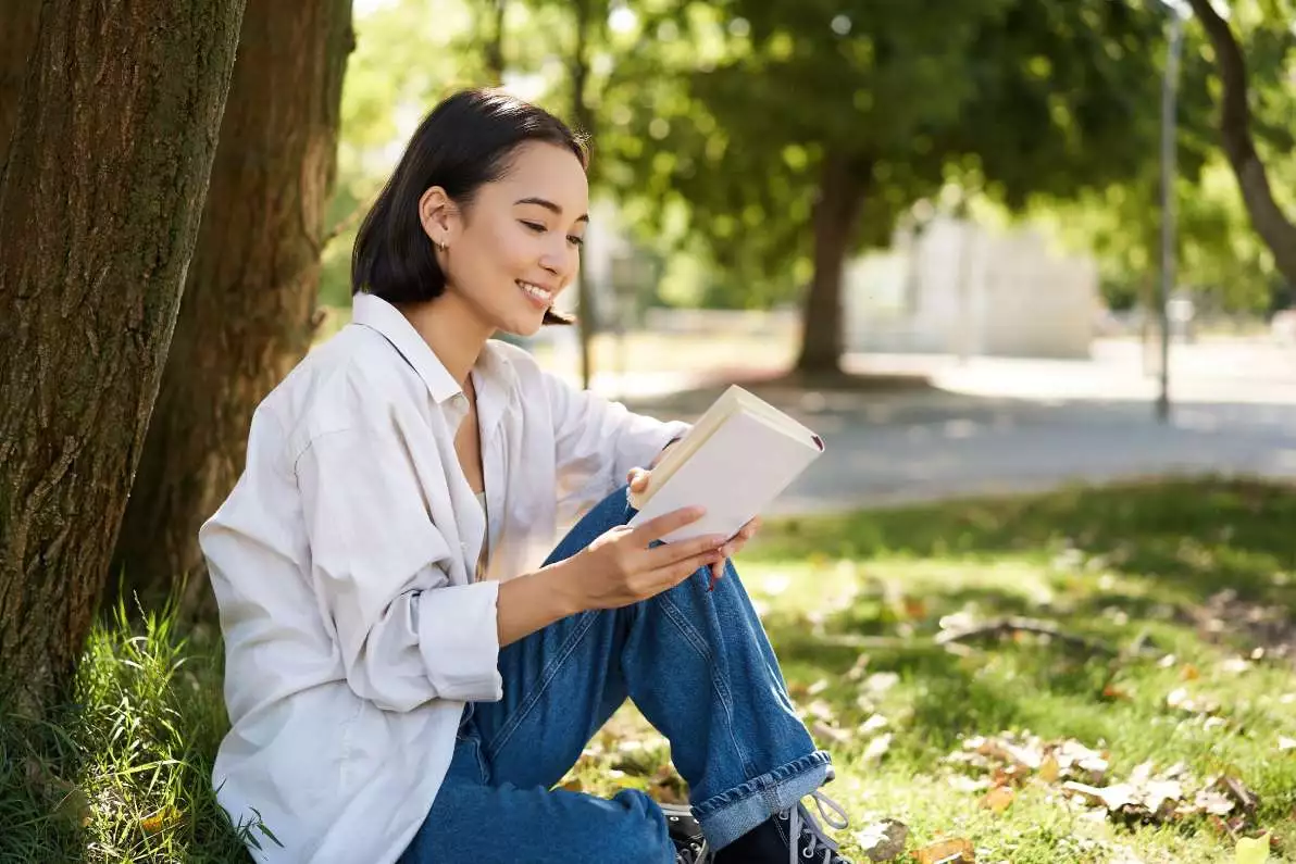 Jeune femme lisant dans un parc