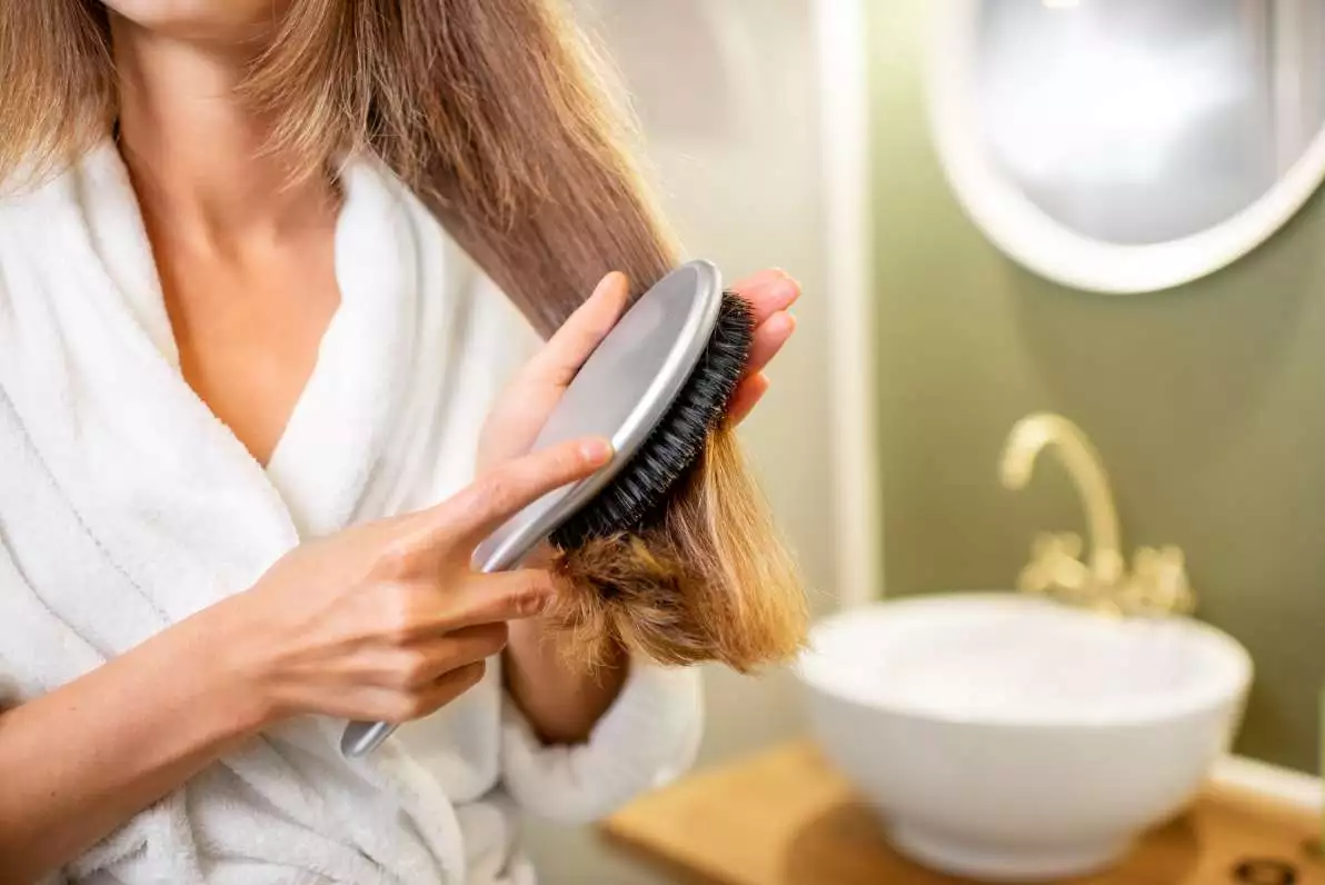 Femme peignant ses cheveux dans sa salle de bain.