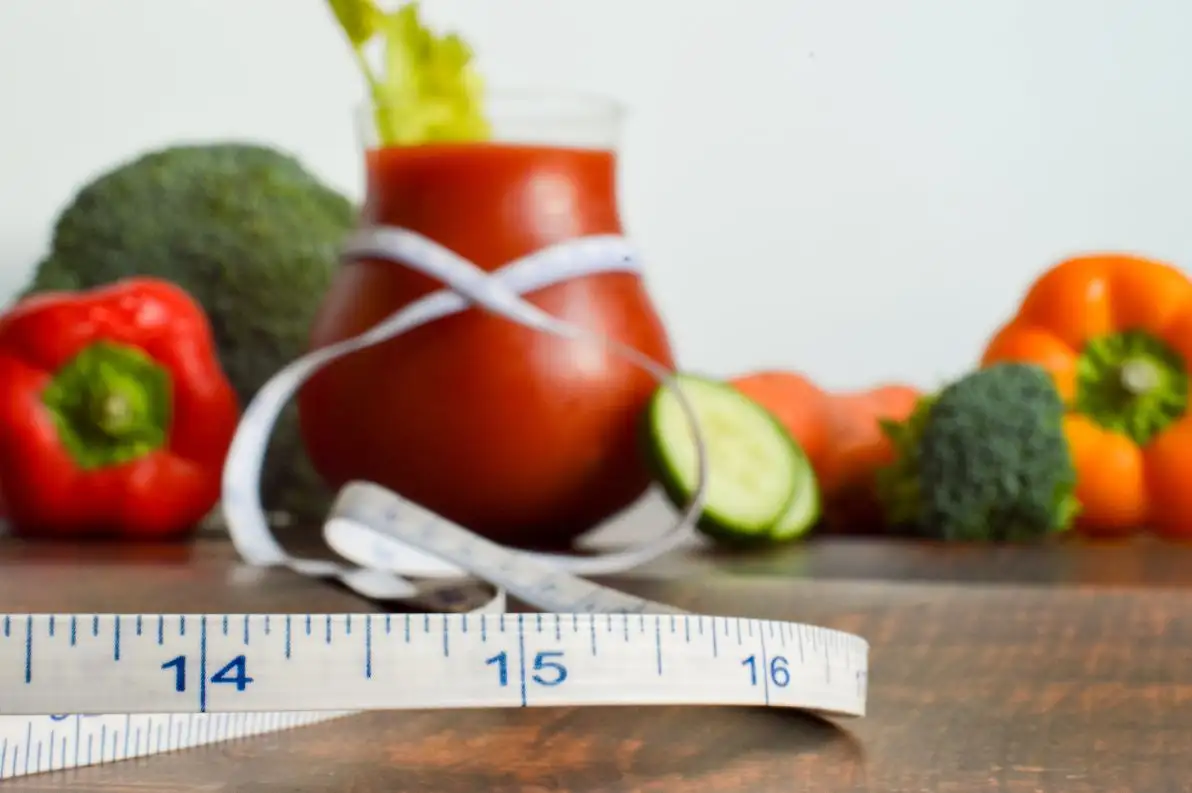 Végétaux sur une table avec un mètre ruban mesureur pour symboliser la perte de poids saine