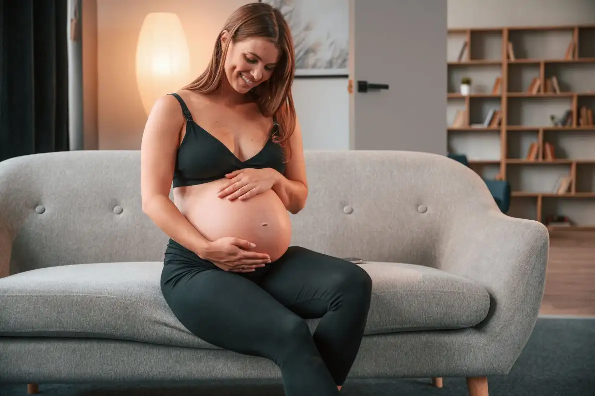 Une femme enceinte est assise sur son canapé