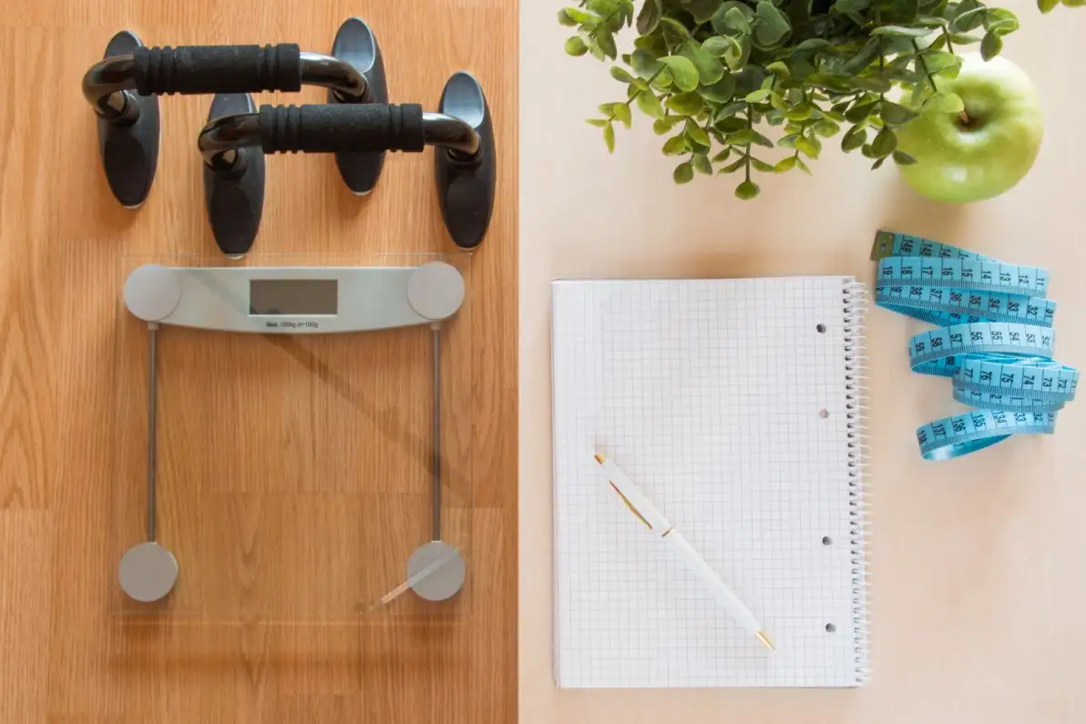 Concept de perte de poids avec une balance, des poids de musculation, une pomme et un mètre ruban