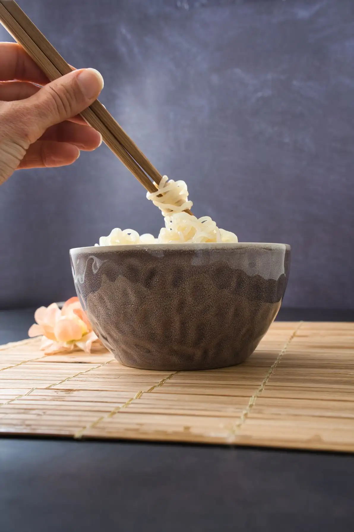 Main de femme tenant des baguettes avec des nouilles de konjac shirataki