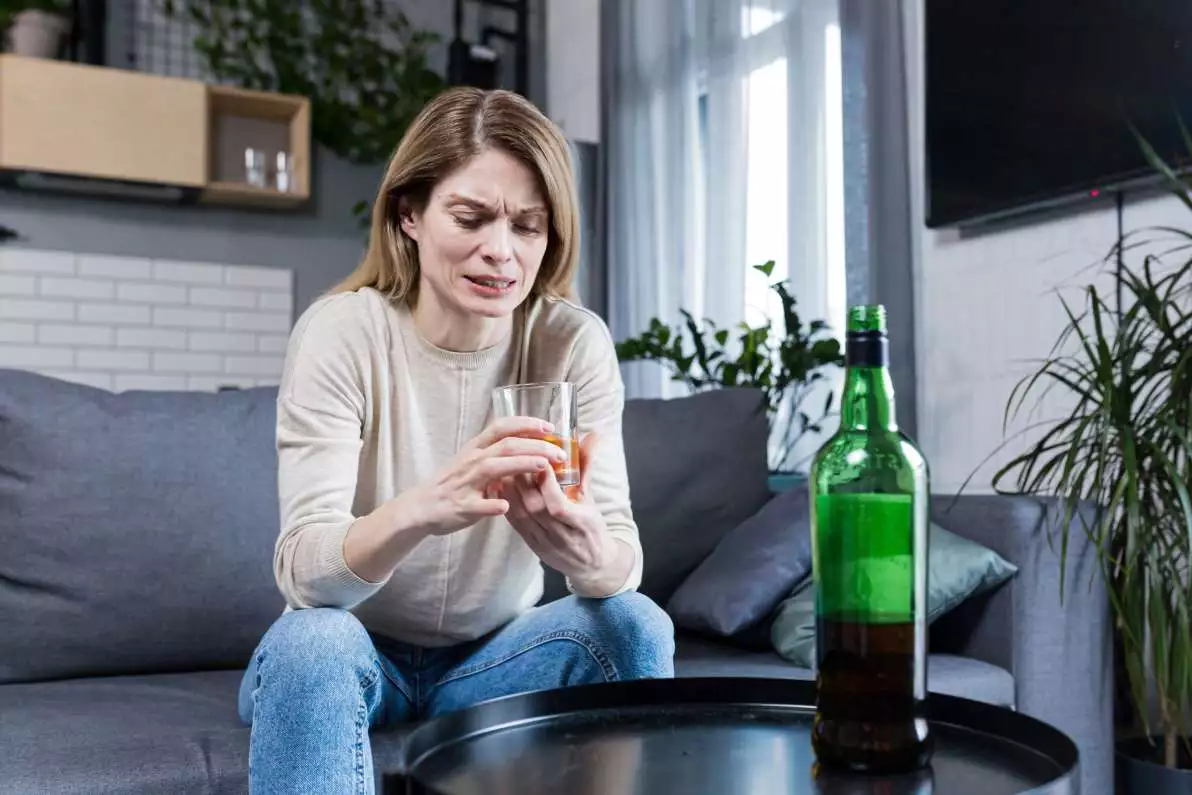 Une femme consommant de l’alcool sur son canapé