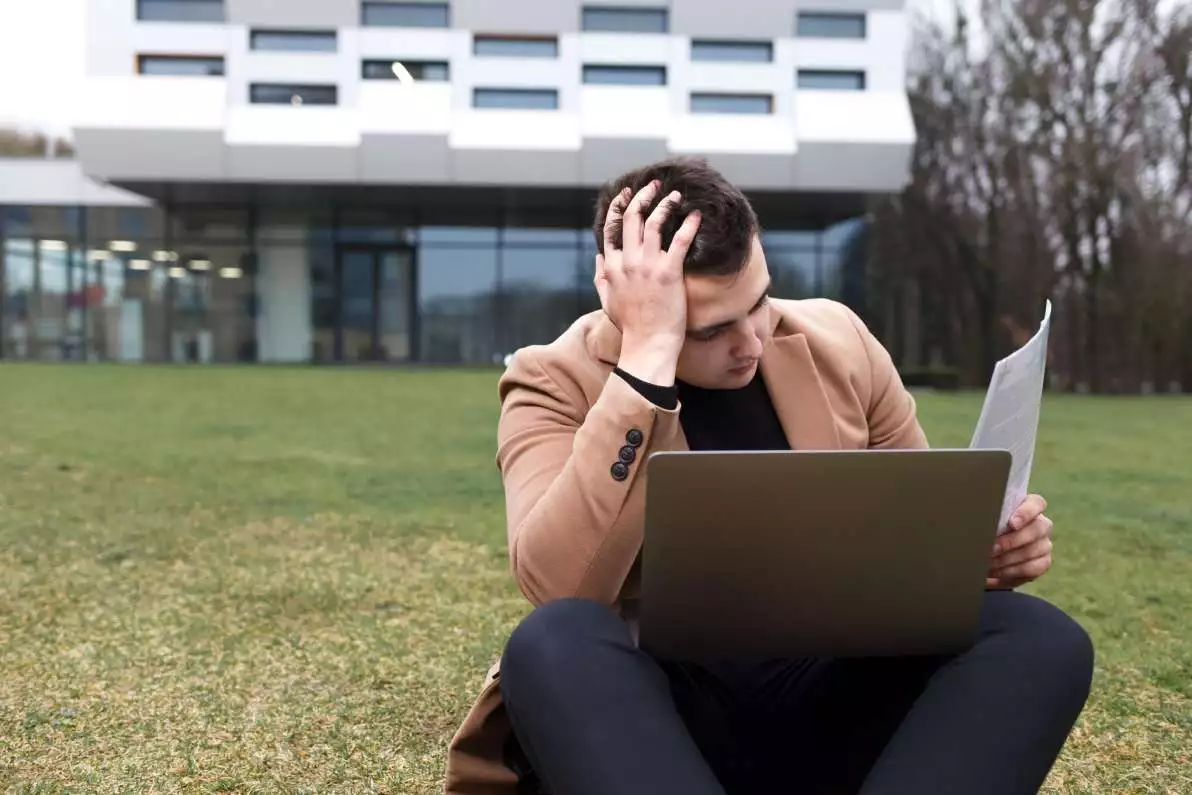 Homme assis qui est dans un état d’anxiété face à l’étendue de son travail