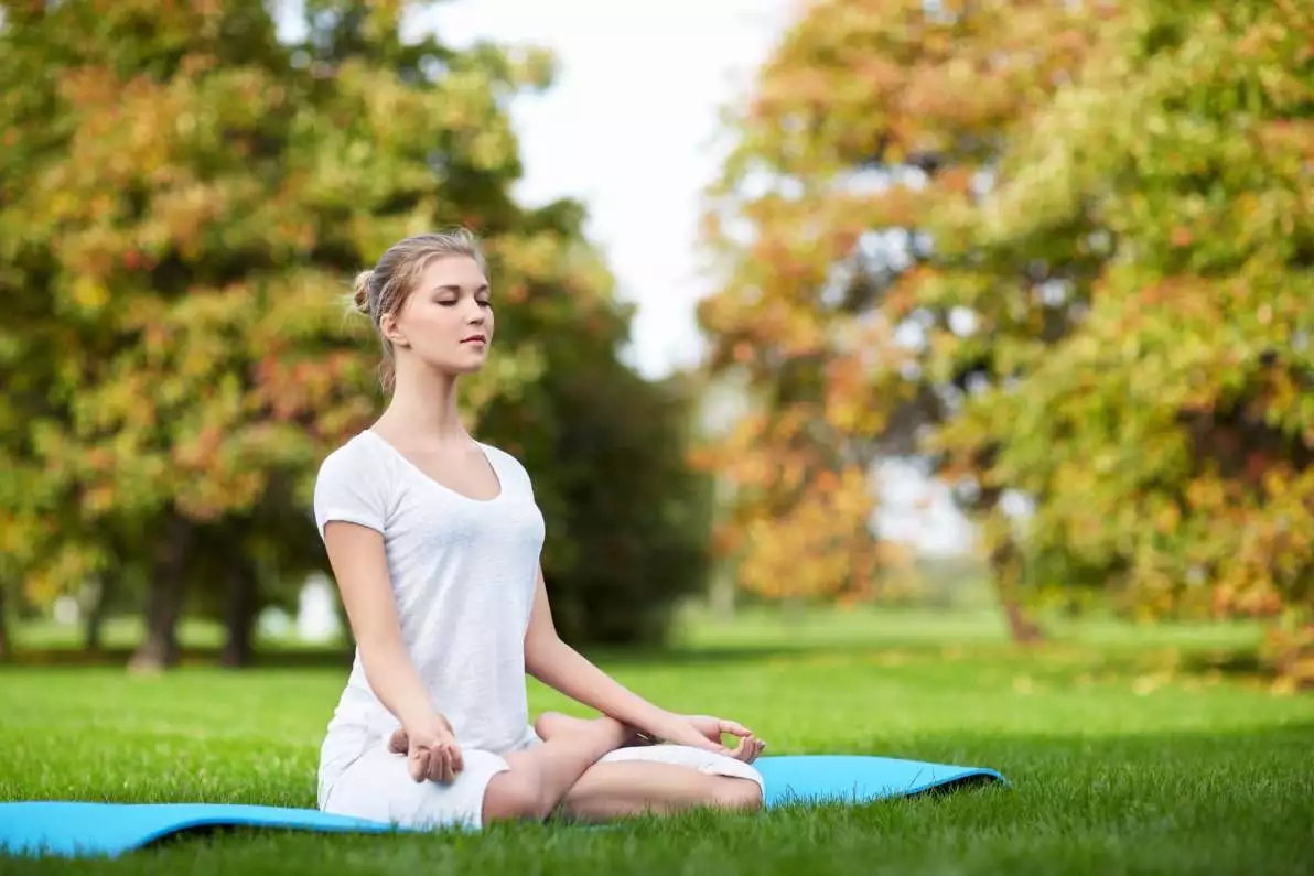 Jeune fille faisant du yoga dans un parc