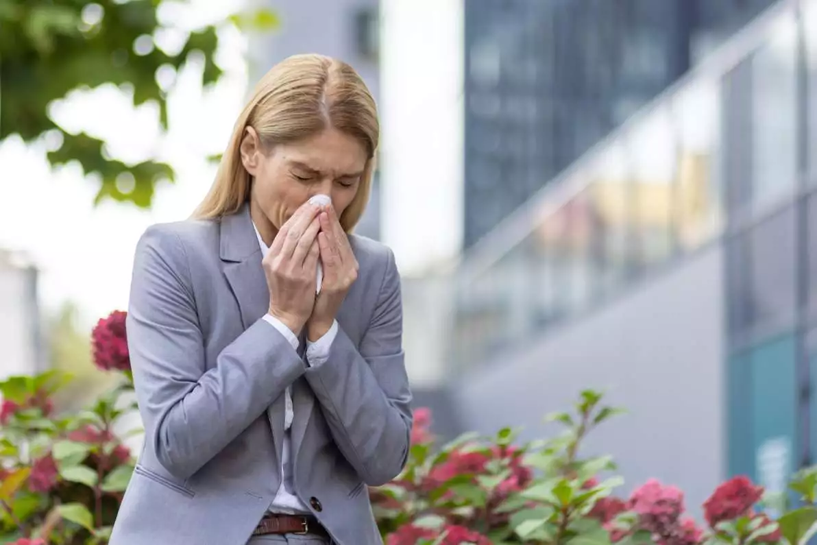 Femme d'affaires éternuant à l'extérieur en raison d'allergies respiratoires.