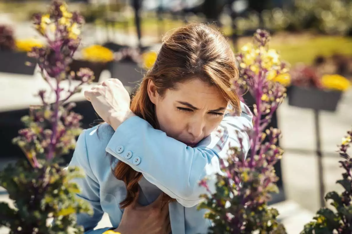 Une dame qui éternue à cause d’une allergie respiratoire.