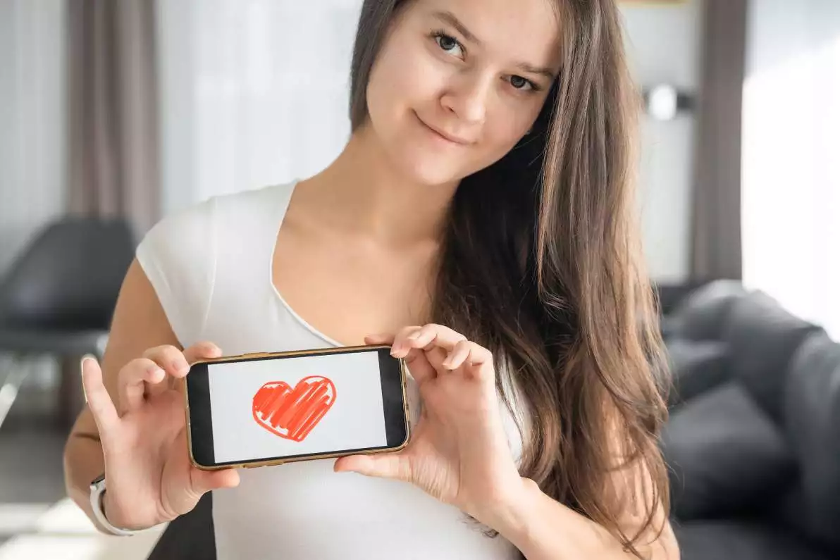 Jeune femme montrant une illustration d'un cœur sur son smartphone, illustrant l'importance de la sensibilisation à la santé cardiovasculaire.